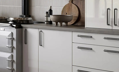 White Slab Door base cabinets with bar handles beside a range cooker